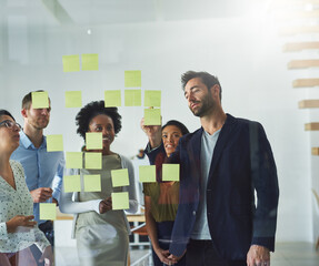 Theyve got a plan of action. Cropped shot of a group of businesspeople working on a glass wall in the office.