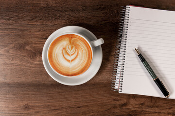 Coffee cup with a notebook and a fountain pen