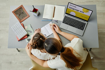 Top view at caring mother embracing daughter while studying together or doing homework, copy space