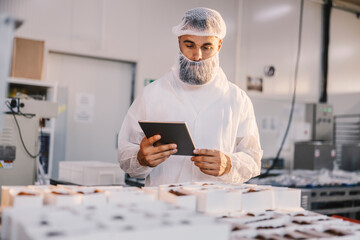 A supervisor with tablet checking on food quality at food factory.