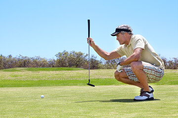 Making this putt worth it. Shot of a mature man lining up a putt on a green.