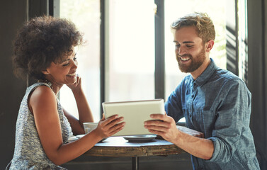 Sharing the love online. Shot of a young couple using a digital tablet together on a coffee date.