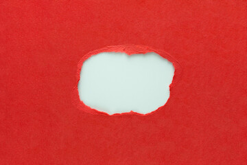 Hole in red paper with torn sides over white paper background with space for text, Torn paper for...