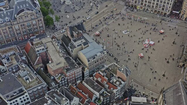 Amsterdam Netherlands Aerial v12 birds eye view drone fly around busy dam square capturing national monument and dutch architectures at binnenstad neighborhood with sun shining through - August 2021