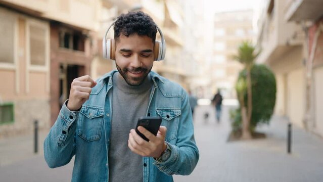 Young arab man smiling confident listening to music at street