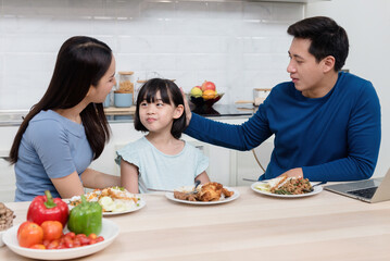 Beautiful woman Handsome man And lovely Asian girls are eating on the kitchen table at home. Everyone is happy. It's a new normal life for the family.