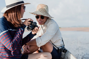 Male and female Asian tourist photographers having fun chatting and view photos in the camera.