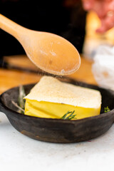 mantequilla derretida con romero  en sarten de hierro  sobre la parrilla. 

mantequilla derretida condimentada en el asador.