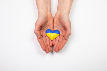 Heart flag of Ukraine in human hands. No war, peace for Ukraine concept.