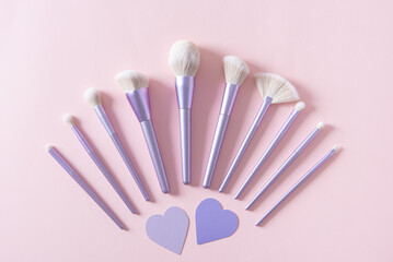 Set of different make up brushes, favourite make up tools on pink background with hearts. Professional make up brushes for visagist. Cosmetic composition. Magazine, cosmetics store