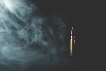 Assault rifle bullet in smoke on black background. Assault rifle bullet vintage background photo. War and death concept. - obrazy, fototapety, plakaty