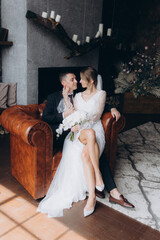 The first meeting of the groom in a black suit and the bride in a white wedding dress with a bouquet in the interior of a photo studio, hotel, on black background