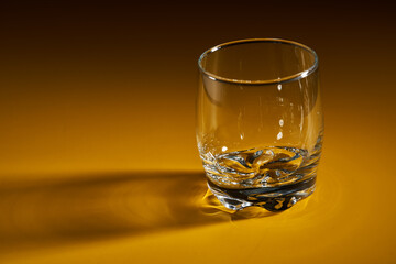Empty whiskey glass on yellow