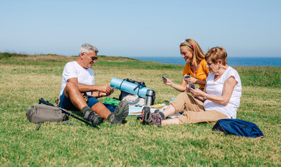 Adult family playing cards sitting on a blanket during an excursion outdoors