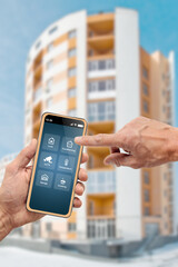 Male finger touching icon of smart home app on smartphone screen, multistory house on the background