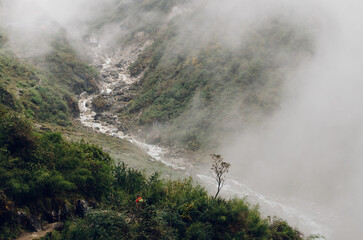 scenic view of the misty valley with river and waterfall in Deurali, Annapurna region, Nepal
