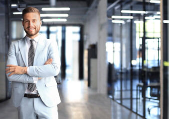 Portrait of happy businessman with arms crossed standing in office