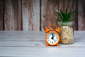 Orange alarm clock isolated on wooden desk. The clock set at 1 o'clock.