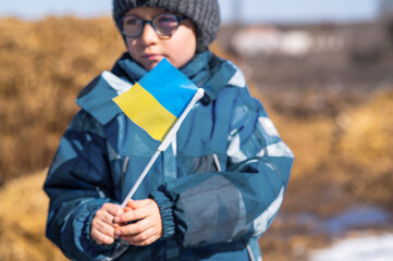 Ukrainian boy holds the flag of Ukraine in his hands. No war. Support for Ukraine