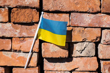 Ukrainian flag on a red brick wall background.