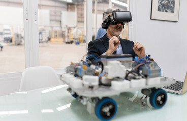 Surprised businessman wearing virtual reality simulator sitting in factory