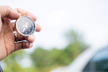 Man hand holding compass on city and car blurred background Using wallpaper or background travel or navigator image.