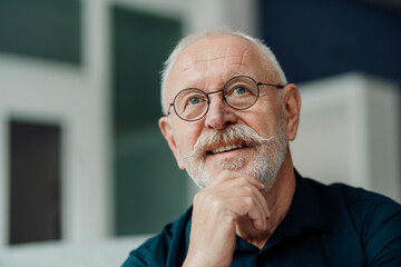 Smiling senior man with hand on chin wearing eyeglasses