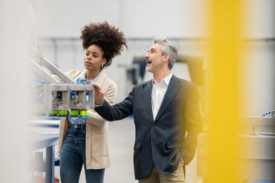 Engineers analyzing machine working together in factory