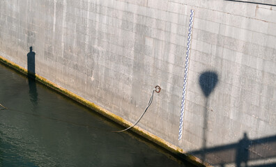 Tape measure line used to calculate the depth of a river, placed on the concrete side of a river shore