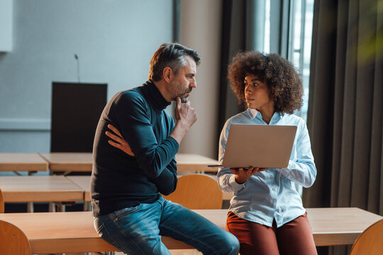 Businessman discussing with colleague holding laptop at work place