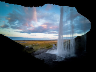 Inside Seljalandsfoss waterfall at dawn in Iceland