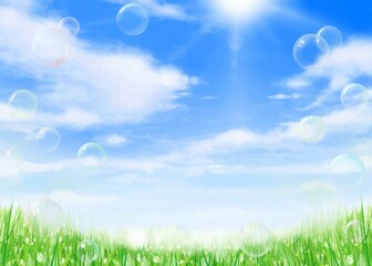 太陽の光が差し込む雲のある青空に虹色のシャボン玉舞う草原の初夏フレーム背景素材