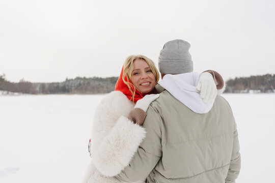 Smiling blond woman hugging boyfriend in winter