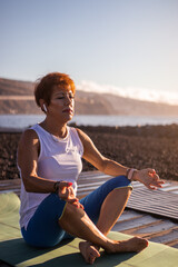 Fototapeta na wymiar Senior woman doing meditation by the sea