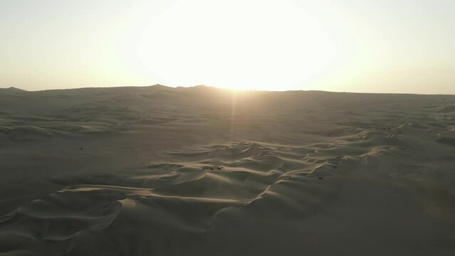 Golden light sunset over Peru desert with sandy tourists exploring