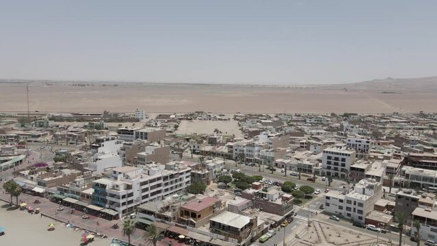 Aerial: Small Pacific town of Paracas Peru in endless sandy desert