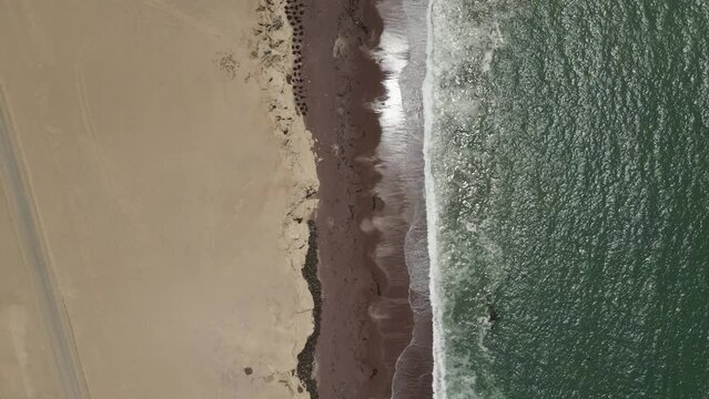 Pacific waves break gently onto desert sandy shore near Paracas Peru