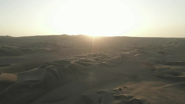 Tourist off-road vehicles ride on endless Chala Desert dunes at sunset