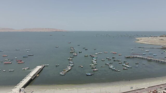 Flyover colorful fishing boats moored in shallow bay of Paracas, Peru