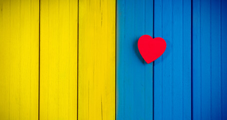 Heart shape on wooden background painted with Ukraine flag colors. Ukrainian love symbol
