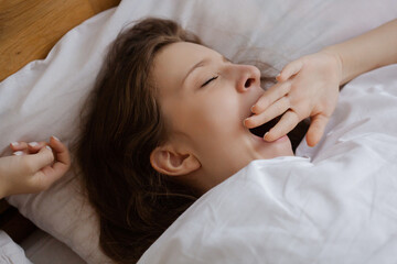Fototapeta na wymiar a young beautiful girl woke up early in the morning in bed and yawns sweetly