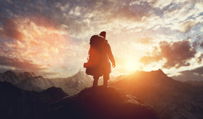 Man on the peak of mountain looking at sunset sky. Trip and adventure. Inspirational.