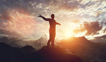 Man walking and balancing on mountain at sunset.