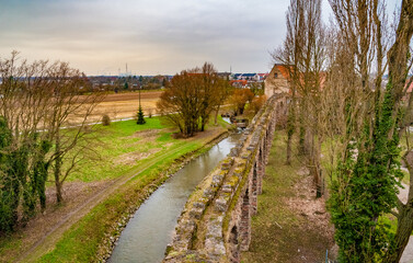 Fototapeta na wymiar Lovely aerial view of the arches of the artificial ruins of the Roman water aqueduct along the Leimbach stream, also serving as a boundary for the English landscape garden of Schwetzingen Palace.