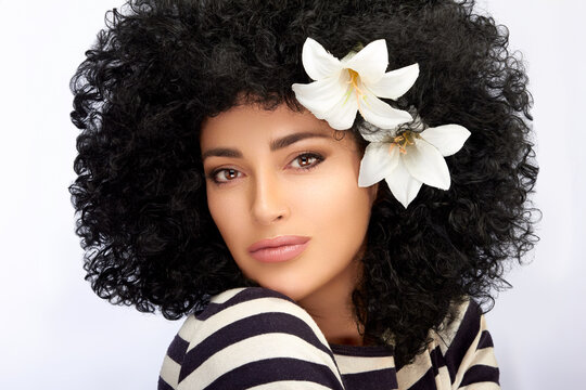 Fashion Model girl with Healthy Curly Afro Hairstyle and Lily Flowers in Hair. Beauty portrait isolated on white with copy space