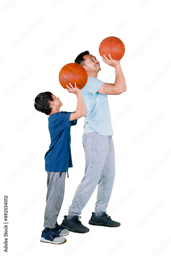 Wall mural Father teaching son to shoot basketball on studio