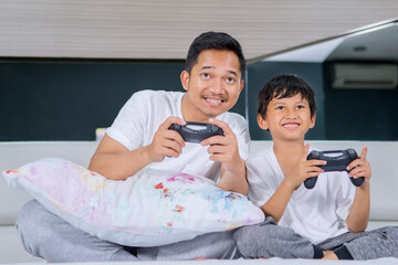 Father playing video game with his son in bedroom