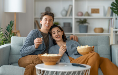 Obraz na płótnie Canvas couple with popcorn sitting on sofa