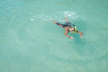 Top view of blond boy in the mask with the snorkel, he swimming and snorkelling in the blue transparent water. Sport concept. Childhood theme. copy space