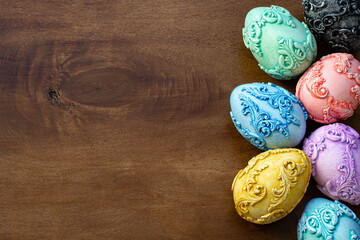 Seven embossed carved vintage Easter eggs on a dark wooden background. Easter background with unusual Easter eggs on the side and space for text.